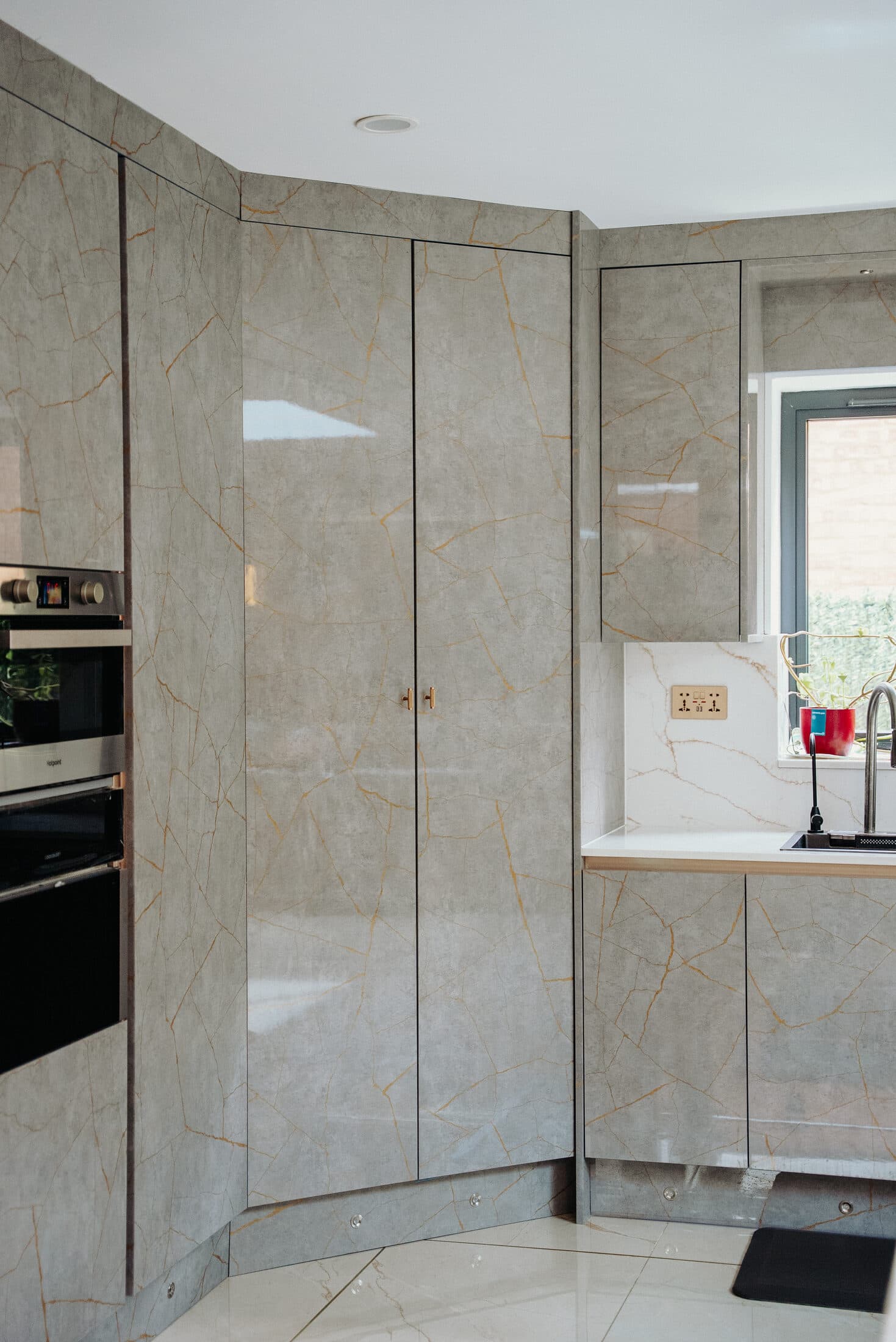 Corner of grey gloss marble effect kitchen units by Sunny Interiors