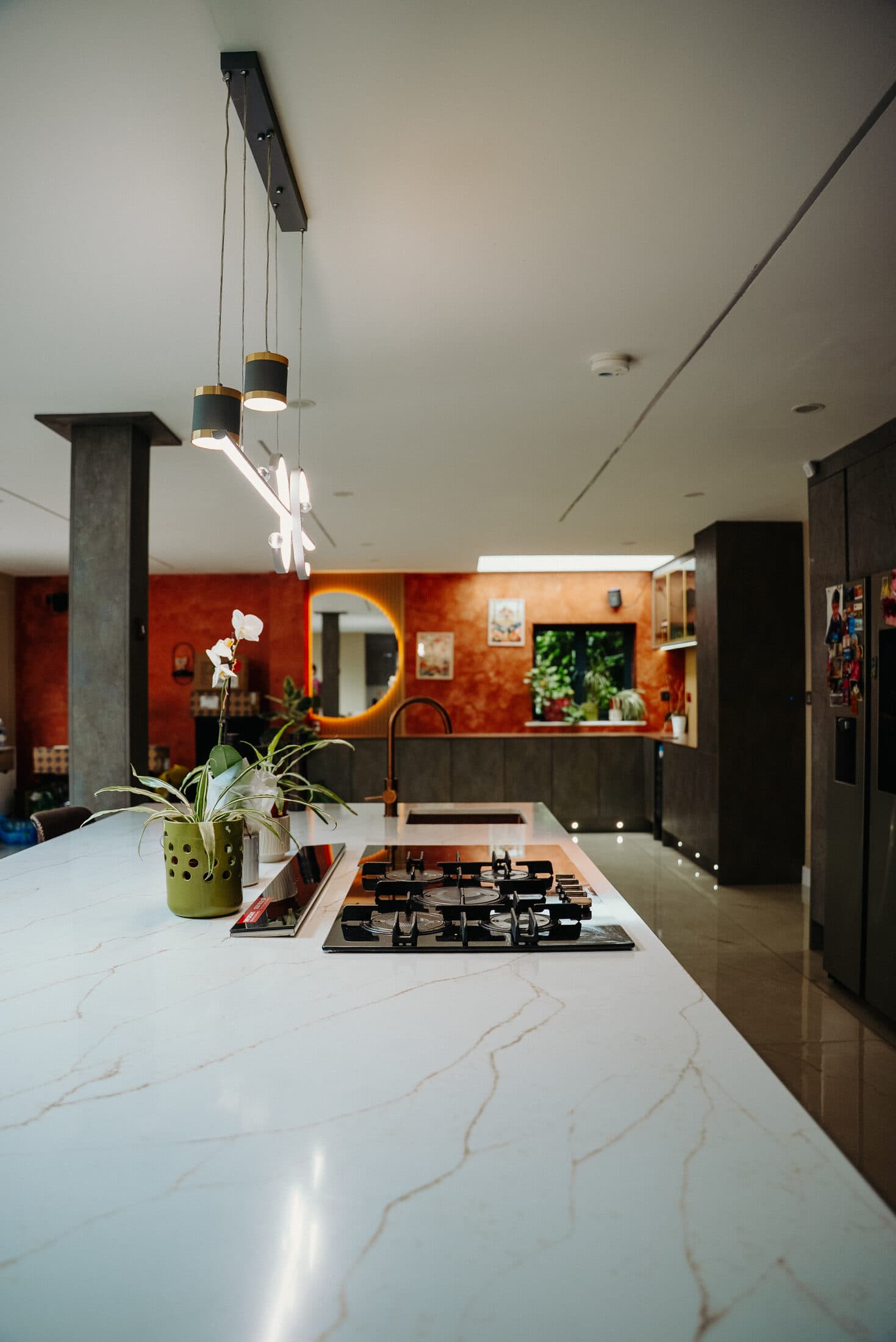 Kitchen island with white marble worktop and orange plaster walls by Sunny Interiors